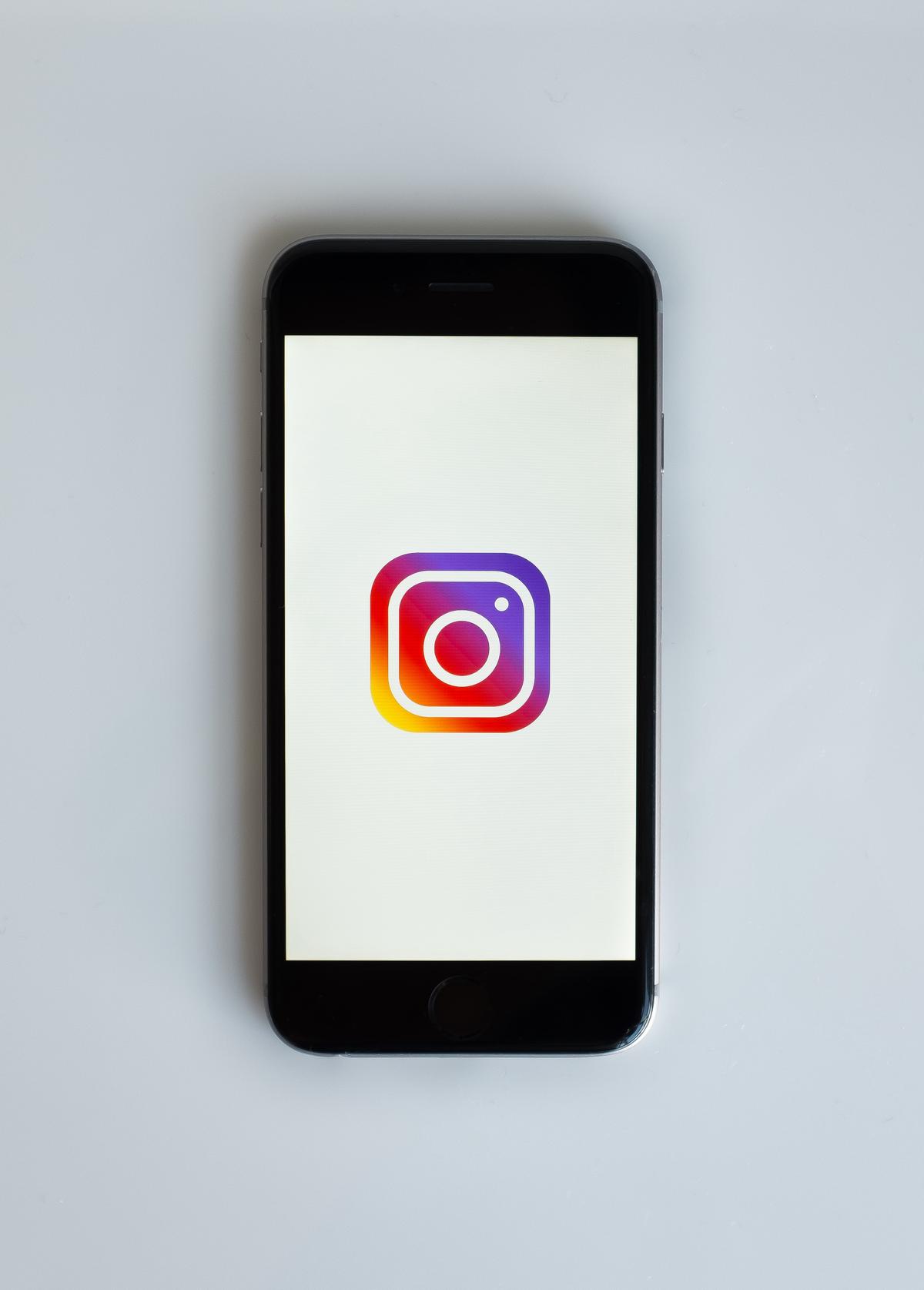 Image illustrating the recent update of Instagram, depicting hands holding a smartphone with the Instagram app on the screen.